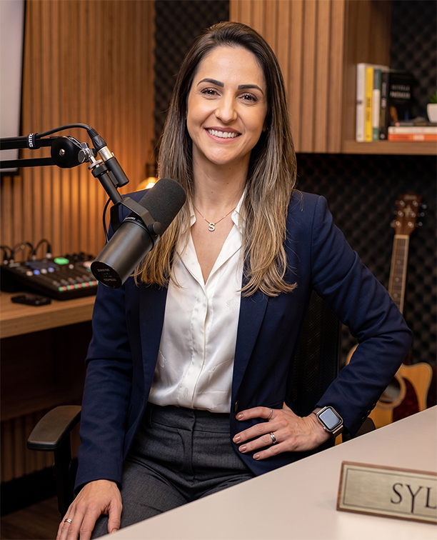 Sylvia Lopes Caiuby sorrindo em estúdio de podcast durante gravação de conteúdo sobre Customer Success